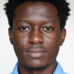 African man with natural textured hair, wearing a blue shirt, looking confidently at the camera.