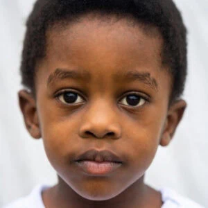 1. Close-up of young Black boy's face with natural hair and calm expression.
