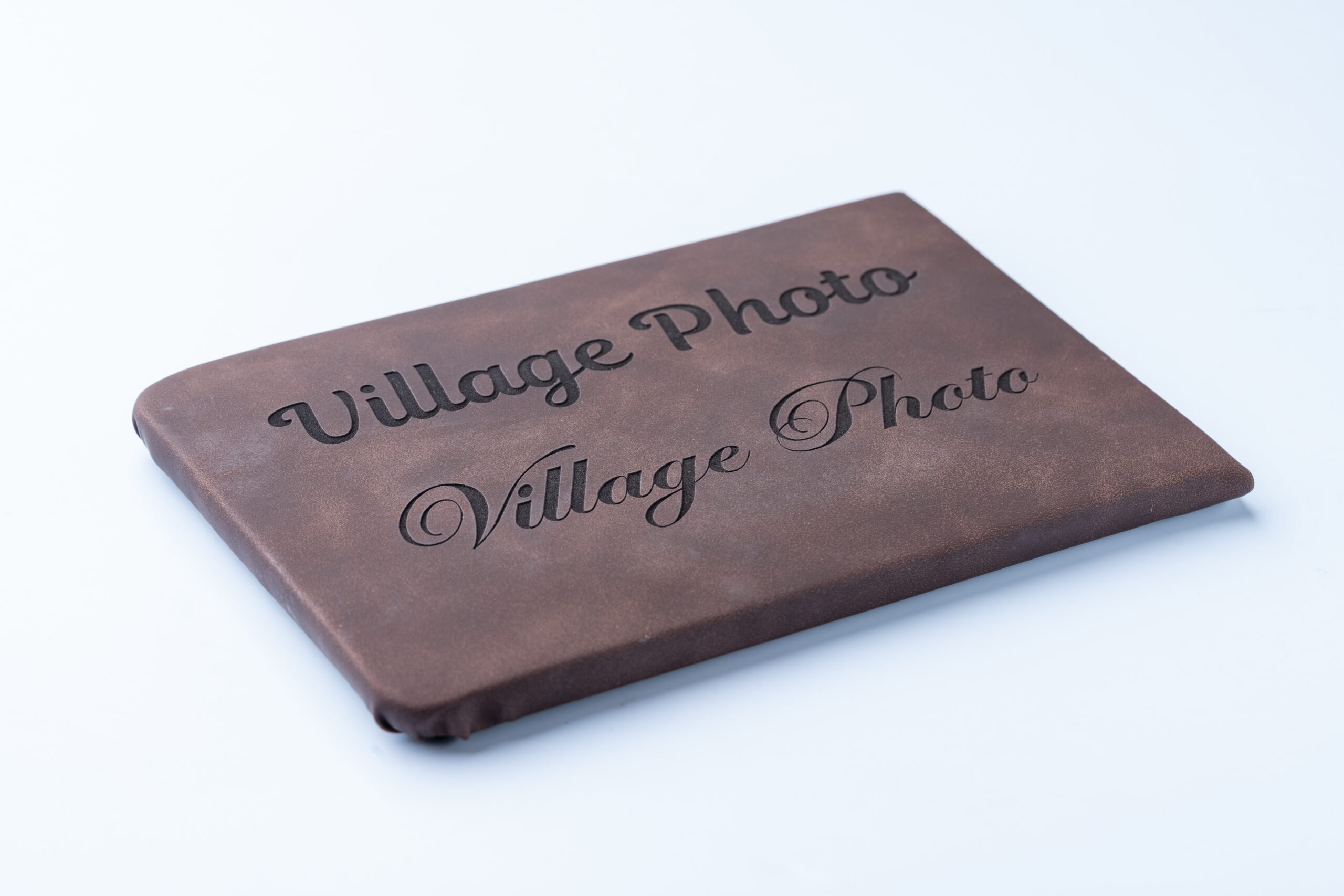 Brown vintage photo album with 'Village Photo' embossed on cover.