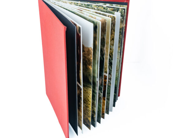 Photo album with multiple landscape photographs in a red cover.