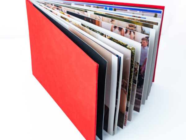 Photo album with multiple pages of photographs in a red cover.