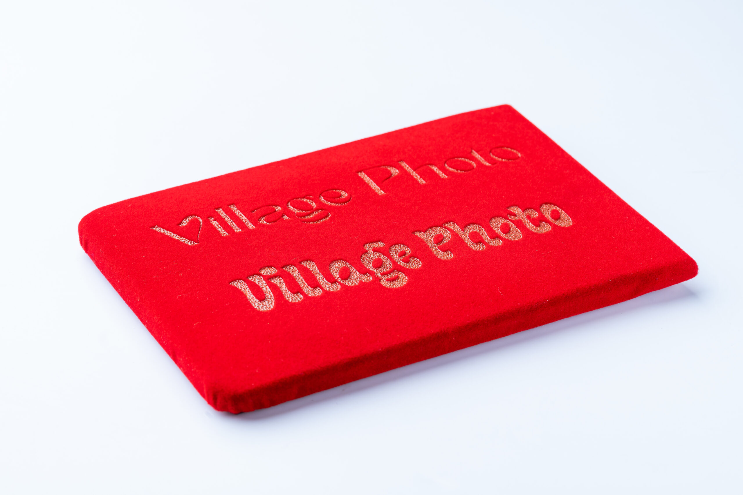 Red fabric sample with 'Village Photo' text for branding or display.